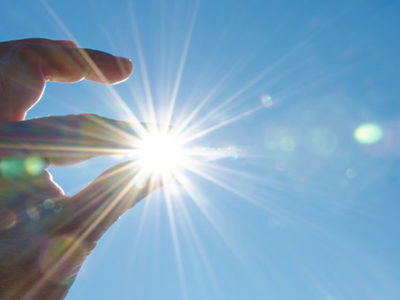 Person Pretending To Hold The Sun Between Their Fingers