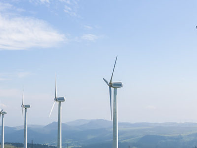 Wind Turbines in front of large green hills representing a clean environment