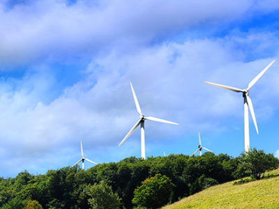 Green hilly pasture with wind turbines at the top