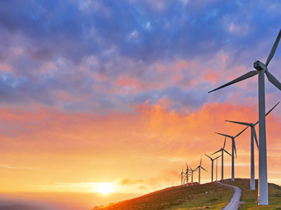 A line of wind turbines in front of a setting sun