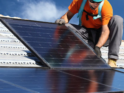 Man installing large solar panels on a roof