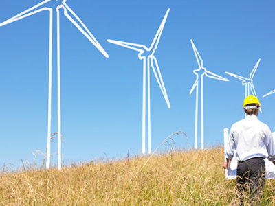 Two guys with hardhats in a field looking to put up wind turbines