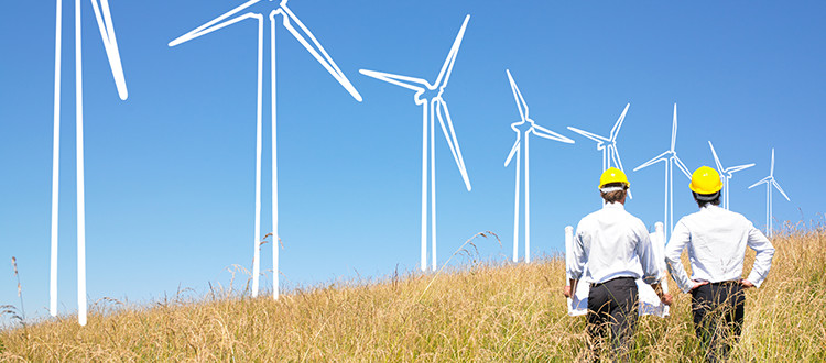 Two guys with hardhats in a field looking to put up wind turbines