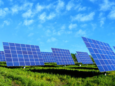 Solar panels in a green field with a blue sky behind them