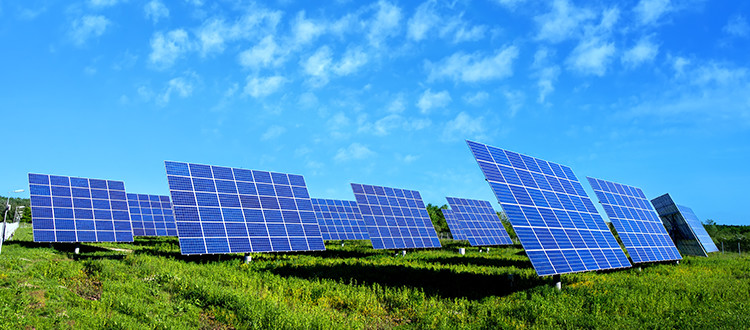 Solar panels in a green field with a blue sky behind them